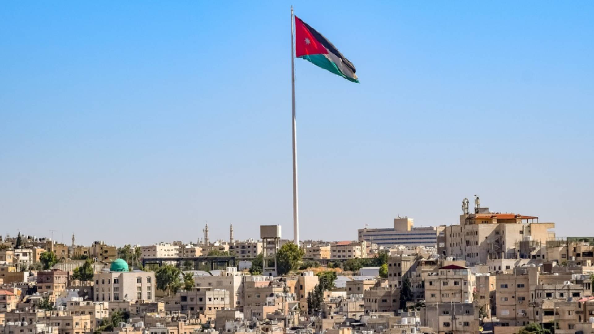 علم الأردن ومشهد من منطقة جبل النزهة في عمان